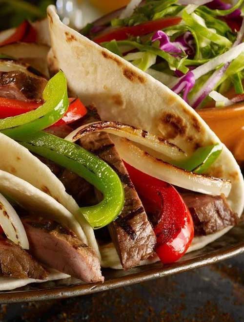 Recipe for Steak Fajitas - Classic Tex Mex, fajitas are typically made with grilled flank steak with onions and bell peppers, and served sizzling hot with fresh tortillas, guacamole, sour cream, and salsa.