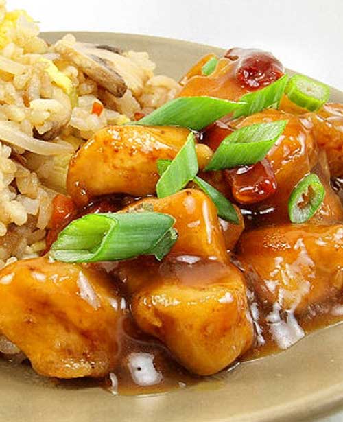 Spicy and sweet orange chicken is served with vegetable fried rice. You may never order take-out again!