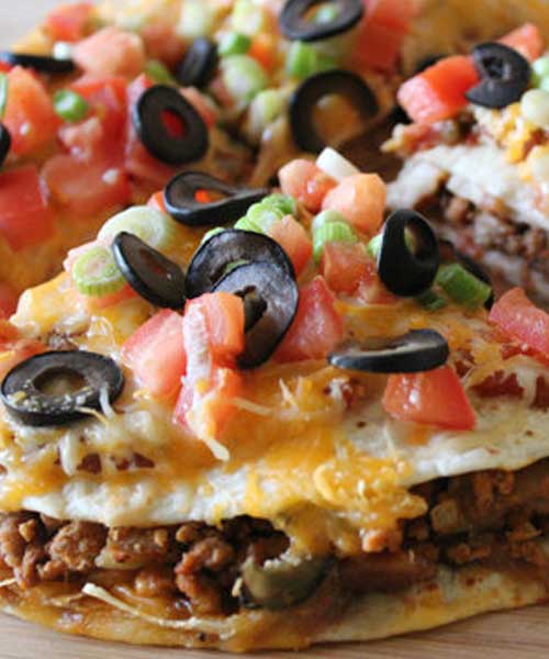 A tasty and easy Mexican-style pizza – delicious corn tortillas topped with beans, beef and all the delicious taco toppings you can imagine!