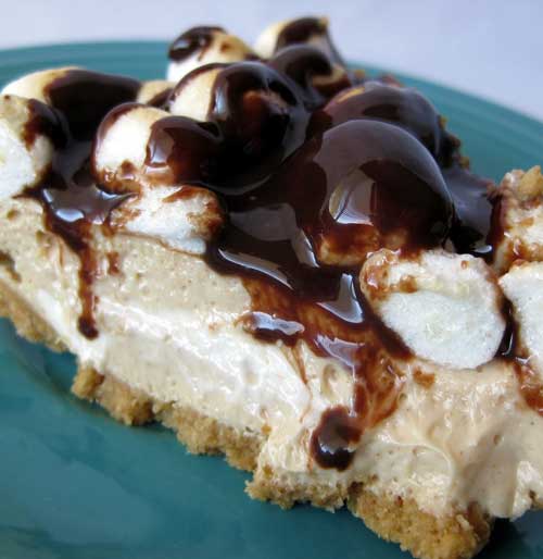 A slice of Peanut Butter Smore Pie on a turquoise plate. The pie is topped with marshmallows and hot fudge sauce.