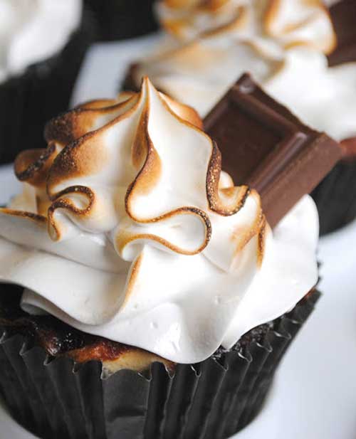 These yummy Smores Cupcakes have everything that S’mores needs: graham cracker, Hershey’s chocolate, toasted marshmallow. At the bottom of these cupcakes is a graham cracker crust, then a  rich chocolate cake, and on top is marshmallow frosting garnished with a square of chocolate.