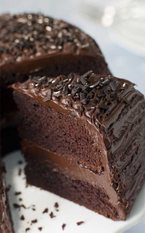 A slice of Old Fashioned Chocolate Buttermilk Cake being removed from a finished cake to show the interior texture.